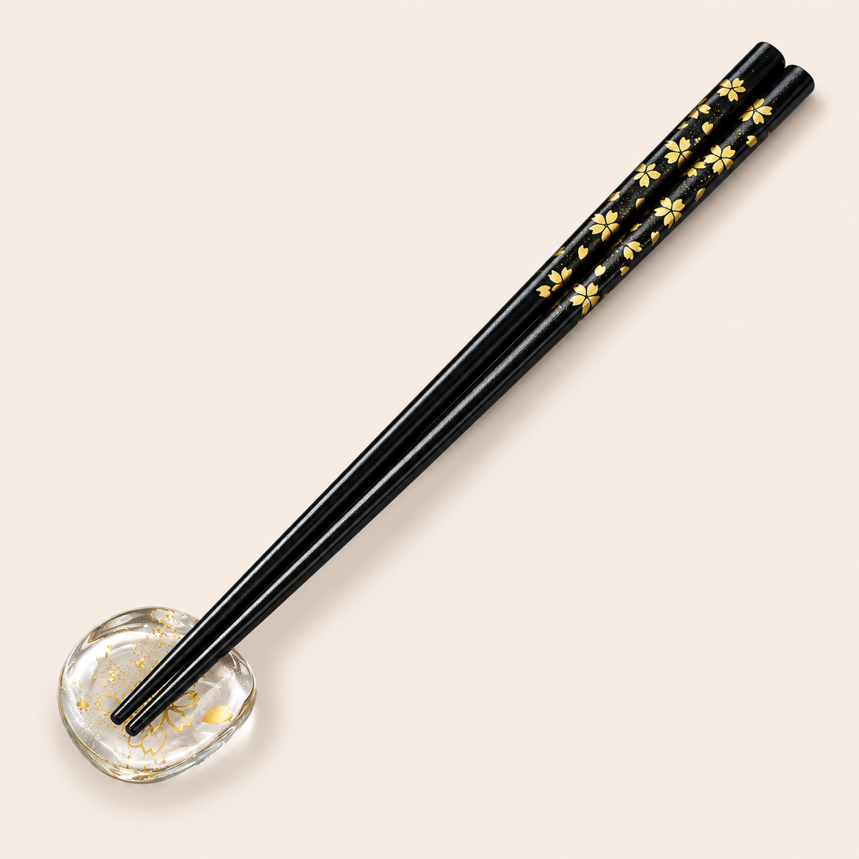 Black lacquer chopsticks with gold cherry blossom pattern on a clear cherry blossom rest
