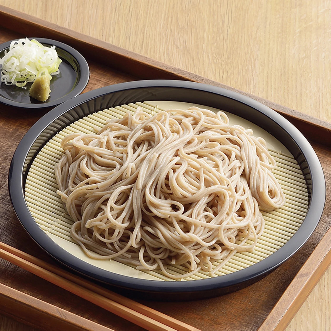 Cold soba noodles on a zaru soba plate with spring onion and wasabi on the side