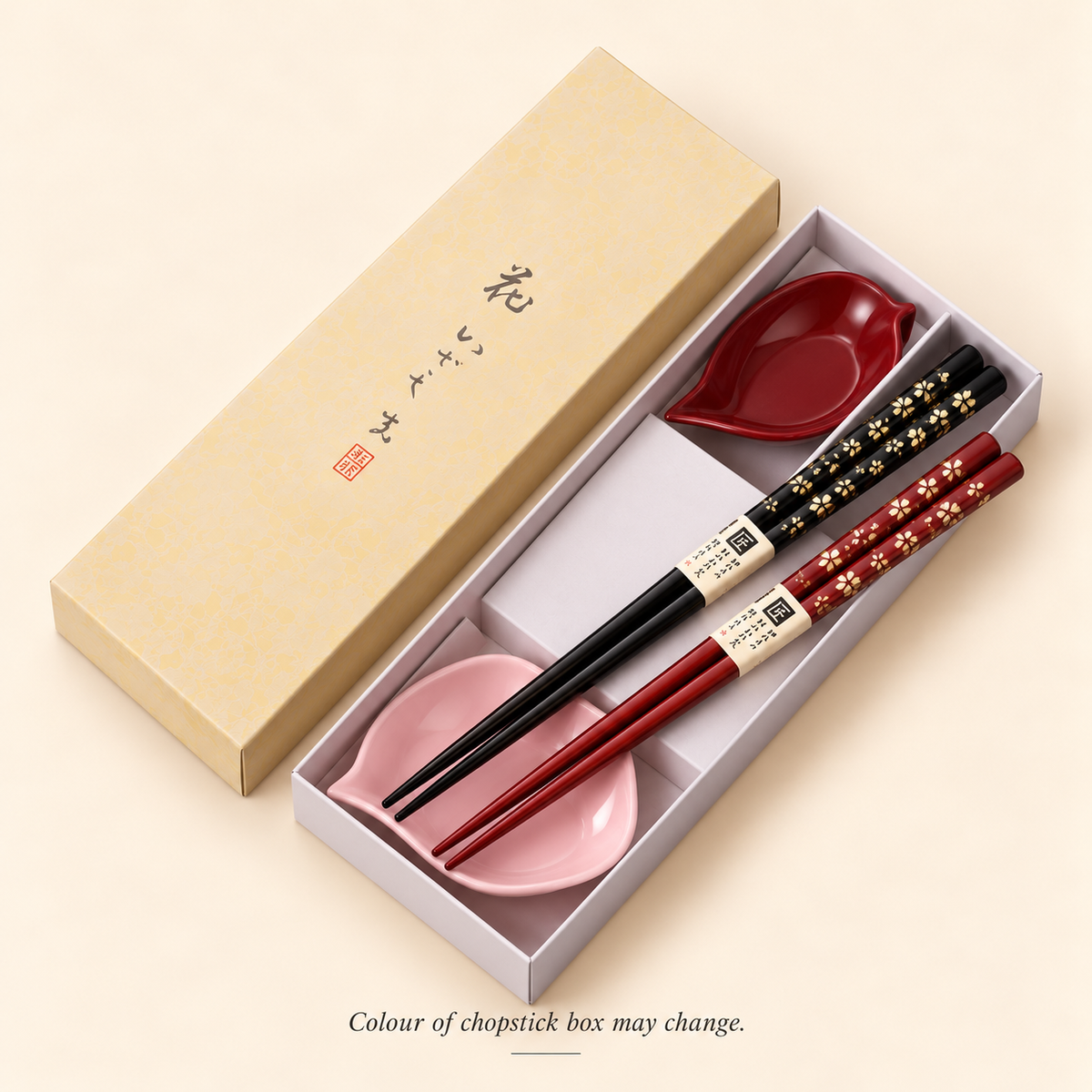 Couple chopsticks and red and pink petal sauce bowls inside the open gift box