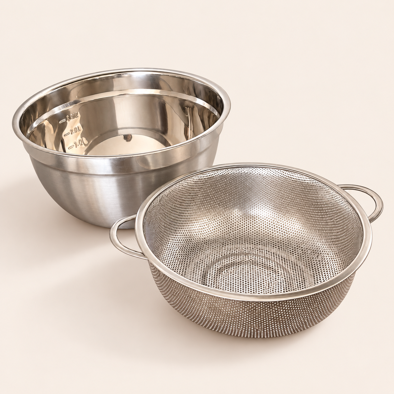 24cm stainless steel strainer with two handles next to its mixing bowl with measuring marks